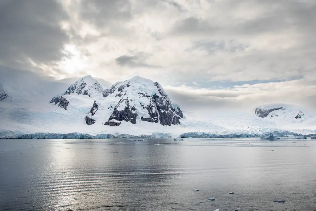 photo of snow-capped mountains with the ocean below