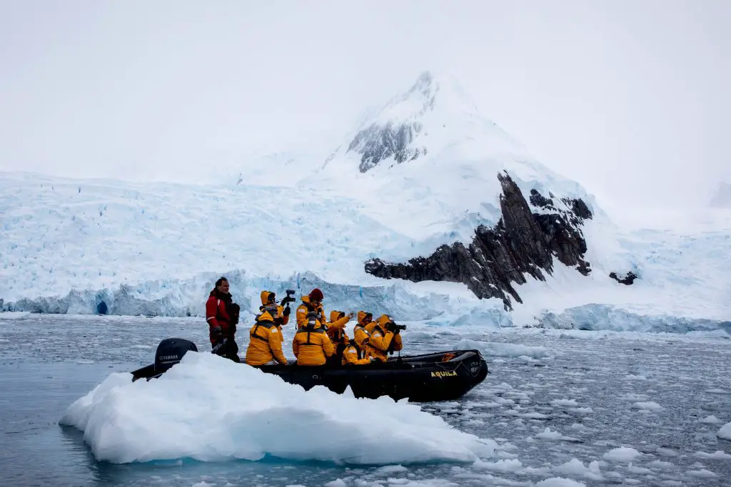 Group of people aboard a zodiac boat taking photos of Antarctica