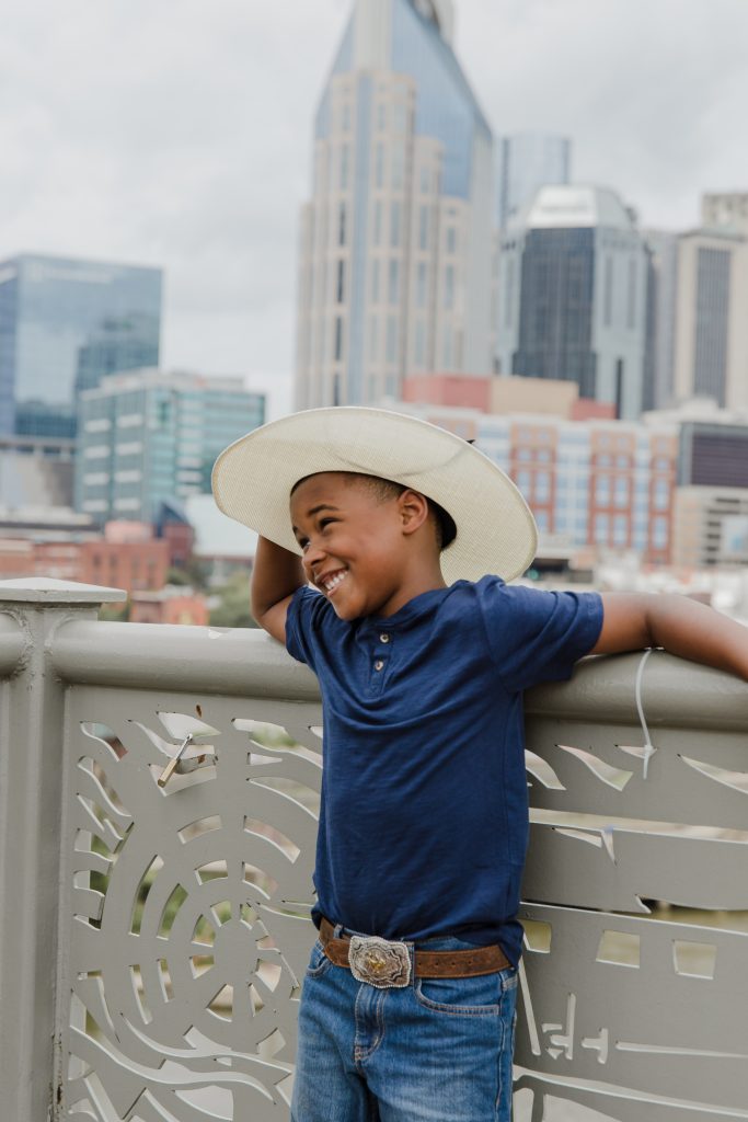 boy with cowboy hat with downtown nashville in the background