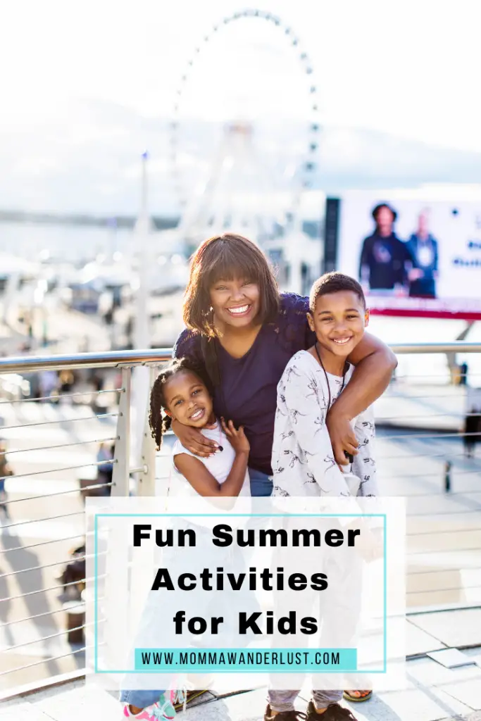 Black woman with two children smiling. Ferris wheel and crowd behind them as they smile at the camera.