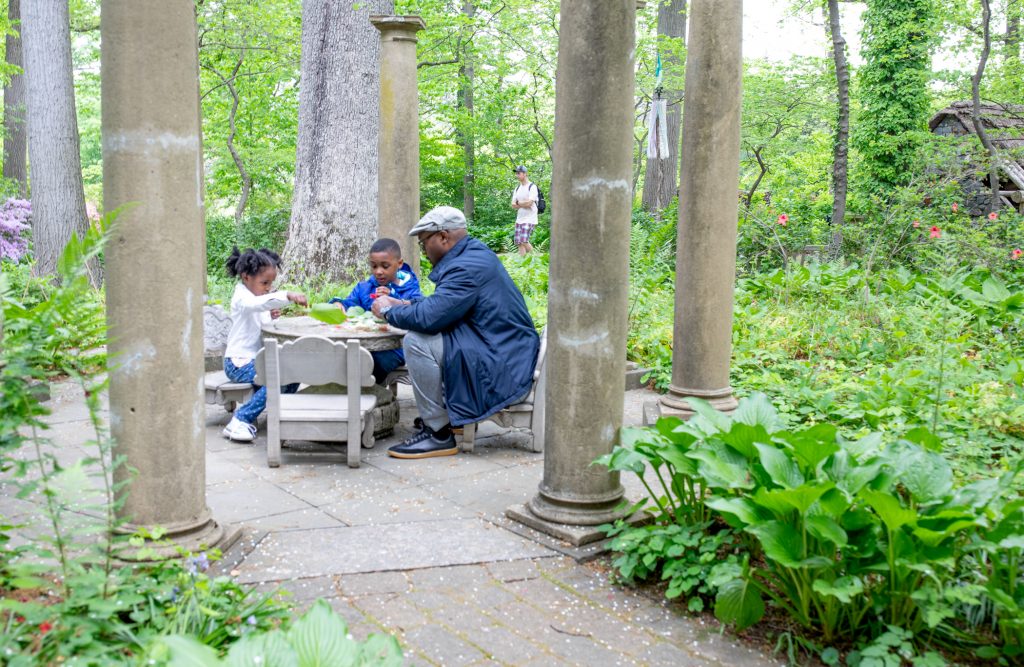 man and two children have a tea party in the enchanted woods in winterthur gardens