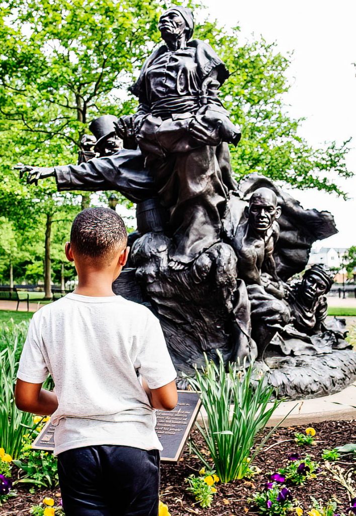 young boy looking at Tubman/Garrett Sculpture outdoors