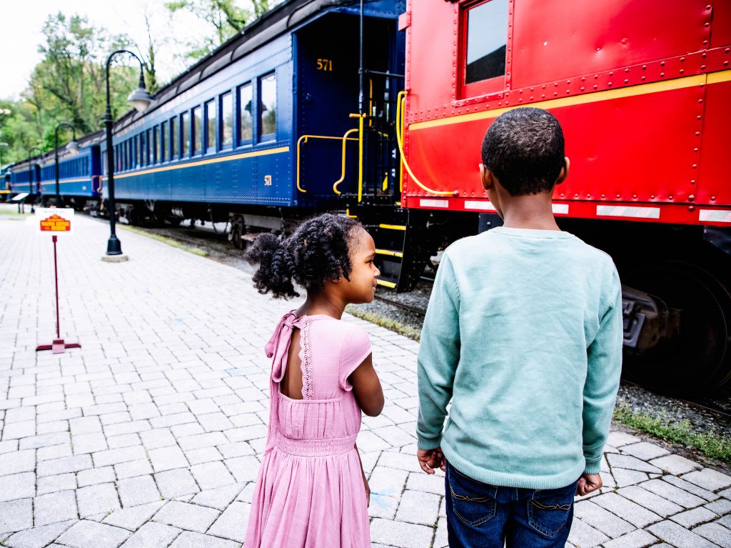 two children standing next to a classic train in wilmington
