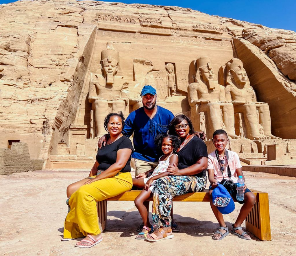 photo of black family seated on bench in front of Abu Simbel monument in Aswan, Egypt