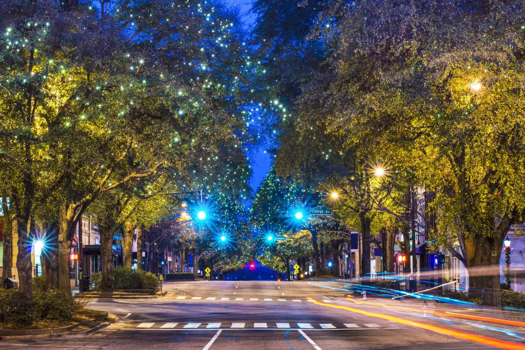 downtown Athens, georgia at night. In the image is one empty street lined by trees.
