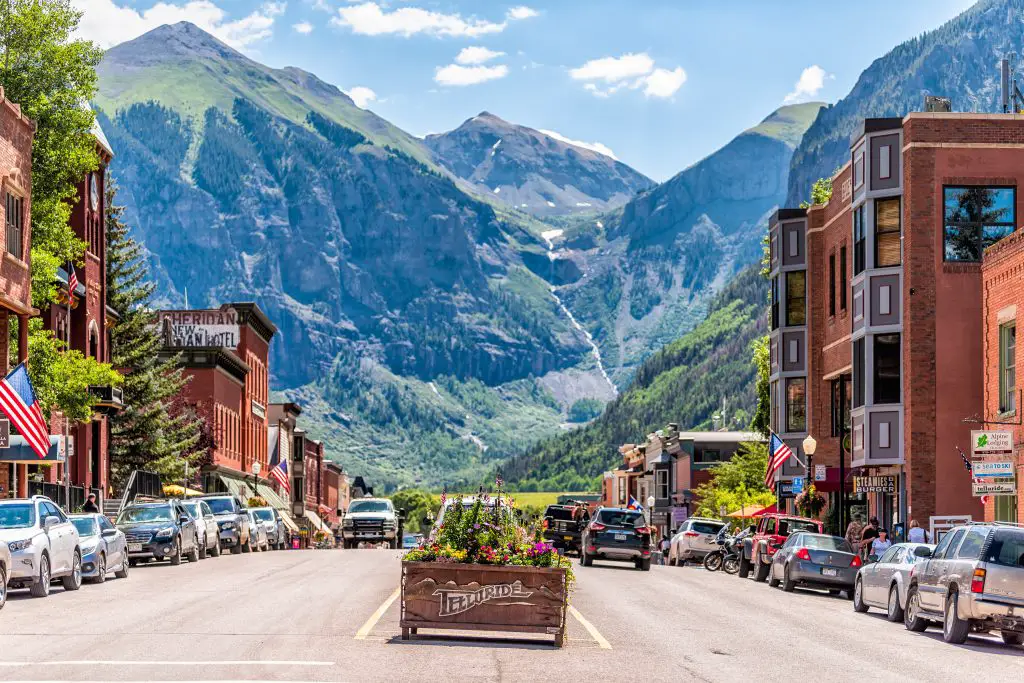 Photo of a city at the bottom of a valley between large mountains. Us Summer Destinations