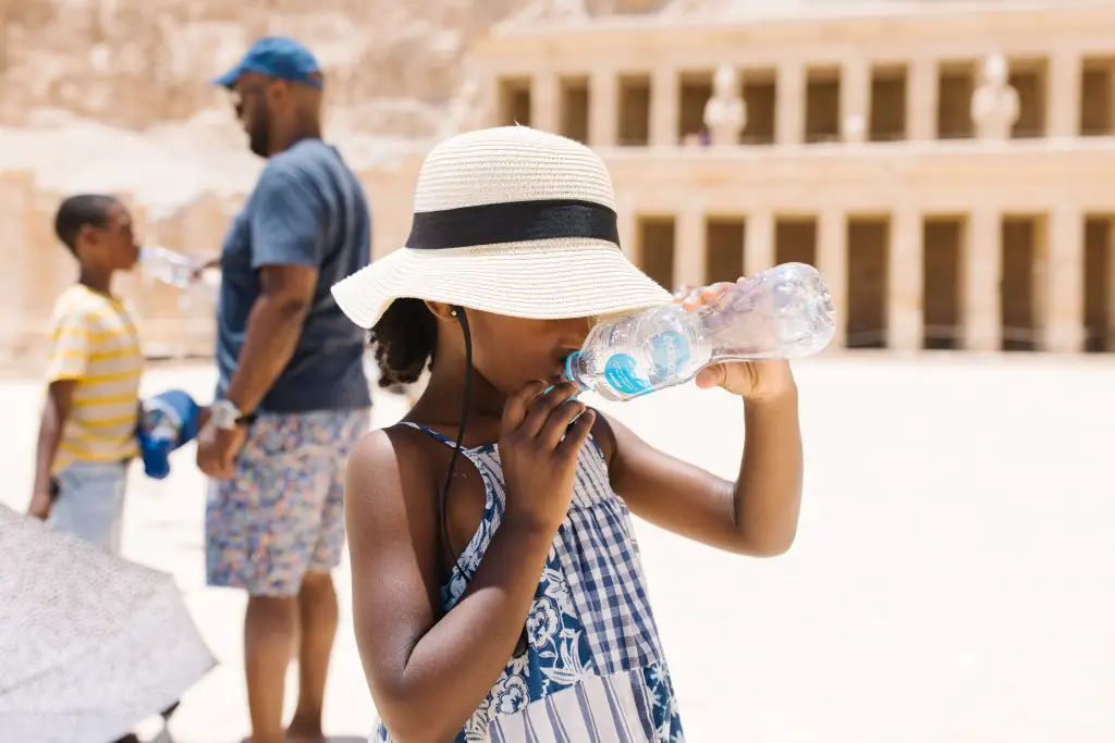 Child drinking water in front of the Valley of Queens in Luxor