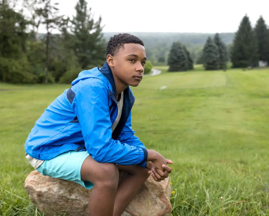 young man sitting on rock looking out at Wisp Resort, Deep Creek, Maryland