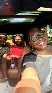 photo of Mom and two kids smiling from inside the car.